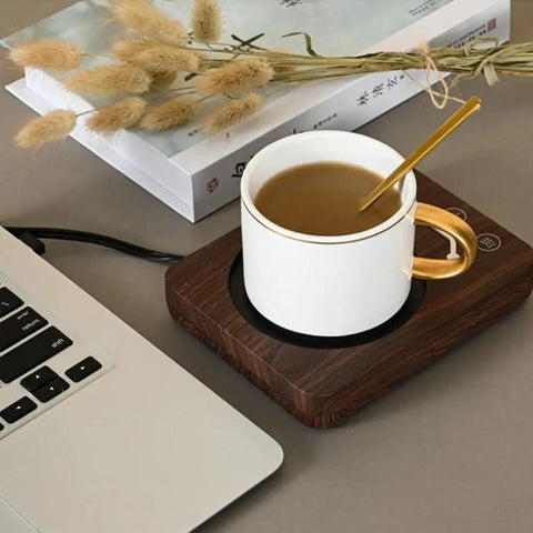 Electric Coffee Mug Warmer With Three Heat Settings And Four Hour Auto Shutoff Keeps Your Favorite Brew Piping Hot For Lazy Desk Setup Or Cozy Kitchen Counters No More Cold Sip Vibes On The Daily with a white mug on a wooden warming tray next to a laptop.