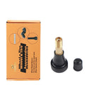 Brass high-pressure tubeless tire valve stem with black base and cap, front view beside orange wheel & tire accessories box.