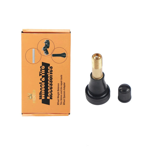 Brass high-pressure tubeless tire valve stem with black base and cap, front view beside orange wheel & tire accessories box.