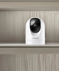 Front view of Indoor 2K Security Cam With 360 Degree Pan Tilt on shelf, compact design for WiFi home surveillance and night vision.