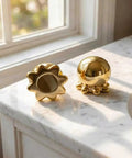 Darn Slick Ceramic Gold Octopus Toilet Bolt Caps Two Pack Snazzy Bathroom Screw Covers on marble counter with sunlight.