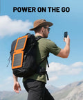 Man using 10W Solar Panel Charger With USB A And USB C Fast Charging For Camping On The Go And Hiking Waterproof Foldable Portable Solar Panel IPX5 Ideal For iPhone iPad And Power Banks attached to backpack.