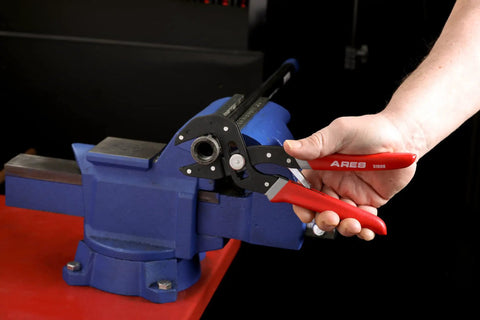 2-Piece Self-Adjusting V-Notch Pliers Set 7-Inch and 10-Inch with red handles used on a blue vice for plumbing and fastener tasks.