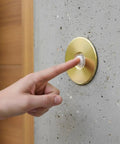 Hand pressing Lit Stucco Pushbutton Doorbell Button with Gold Rim Pearl Button 5/8 Inch Diameter on 2-1/2 Inch Aluminum Plate
