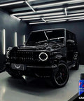 Front-quarter view of a black Mercedes G-Wagen with CARPRO CQUARTZ UK 3.0 coating kit bottle in a studio.