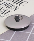 2pcs Rubber Bathtub Drain Stopper Black for Bathroom and Laundry with metal ring and flat cover on a textured surface.