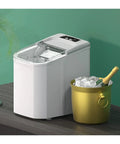 Effortless Portable Ice Cube Maker No Stress Countertop Machine chilling ice cubes beside a gold bucket and champagne bottle.