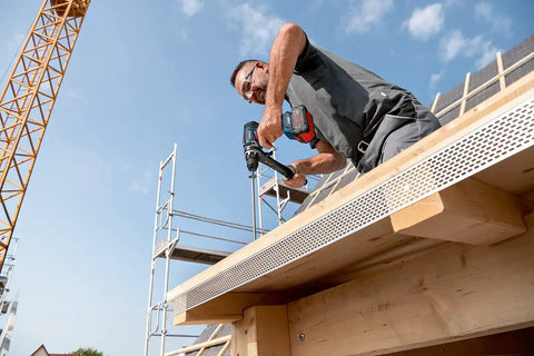 Man using 18V Cordless Combi Drill with 150 Nm Torque Brushless Motor Pro Grade Power Tool on construction site.