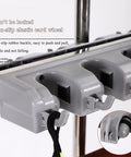 Close-up of non-slip rubber holders on Sturdy Stainless Floor Standing Broom And Mop Rack On Wheels Movable Cleaning Tool Cart.