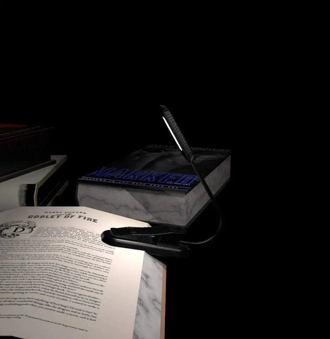 Grab And Go Clip On Book Light With 12 LED USB Rechargeable Battery illuminating an open book on a desk for night reading.