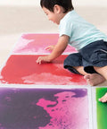 Child playing on Six Assorted Color 12 by 12 Inch Liquid Floor Tiles Set for Kids, Kid Friendly Sensory Floor Tiles Where Color Flows