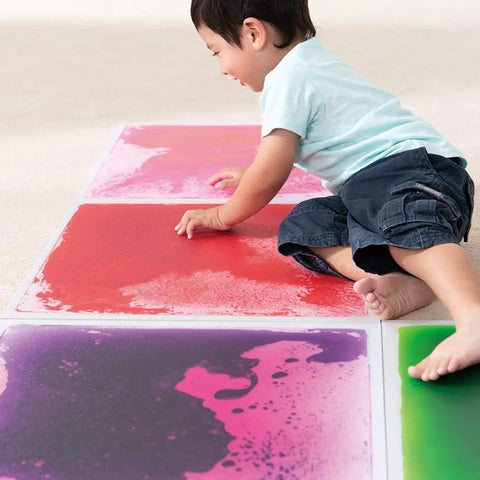 Child playing on Six Assorted Color 12 by 12 Inch Liquid Floor Tiles Set for Kids, Kid Friendly Sensory Floor Tiles Where Color Flows