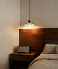 Wood Grain Pendant Light, 3 Color LED Resin Hanging Fixture for Bedroom illuminating a cozy bedside with modern decor.