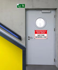 2 Pack Emergency Exit Only Sign Not For General Use Clear As Day Warning Label mounted on a gray door in a commercial stairwell.