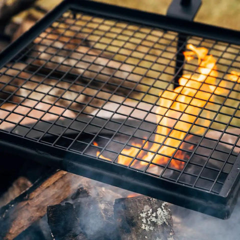 Adjustable Swivel Grill Grate for Open Fire Cooking With Spike Pole Steel Mesh Wire Grate over campfire with flames.