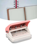 Ultimate Handheld 3-Hole Paper Puncher with 5-Sheet Capacity, shown in pink, durable metal build, next to spiral notebooks.