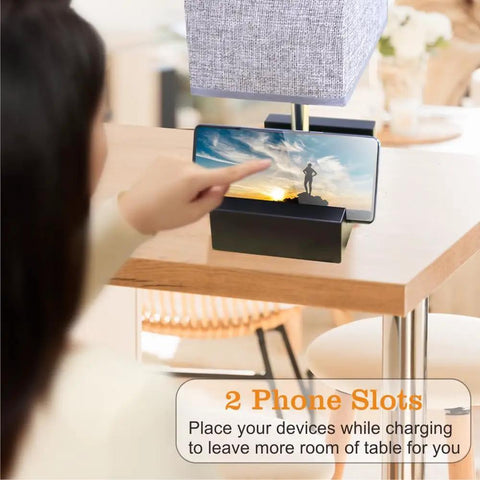 Close-up of fully dimmable bedside table lamp with dual phone stands and AC outlet, set of 2, light grey with a phone in slot