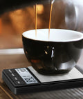 Digital Coffee Scale With Timer For Espresso, 1000g By 0.1g Precision, placed under a cup on a coffee machine.