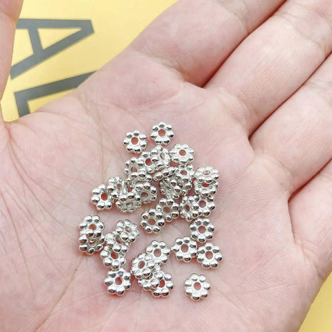 Hand holding 1200pcs Silver Flower Shape Septal Beads, Daisy Spacers CCB Spacer Beads For Bracelet Necklace Earring Jewelry Making