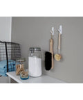 Two beige cleaning brushes hanging on wall using Large Utility Hook Mega Pack 14 Count For No Fuss Damage Free Hanging Holds Strong On Painted Walls