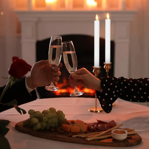 Couple toasting with champagne glasses near 36 Piece Flameless Taper Candles Set, 10 Inch Battery Operated LED Tapers