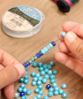 Person using Hook Eye Needle For Beading 10 Inch Long Extra Fine Bead Stringing Tool for Quick Bead Loading onto Cord.