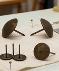 Heavy Duty Antique Brass Upholstery Tacks For Diy Furniture Repair Leather Crafting Auto Interiors Includes Thirty Solid Metal Clavos With Round Heads That Grip Tight Without Splitting Wood For A Sick Makeover Fix, showing various brass tacks on a cloth surface.