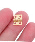 Close-up of Tiny Brass Door Hinges 8x10mm Set Of 100 for Wooden Jewelry Boxes held between fingers.