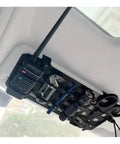 Rugged Tactical Sun Visor Rack With Reinforced Panels And Secure Lash Bands For Tesla Cybertruck holding tools and a radio.