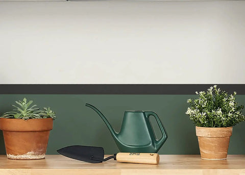 Tempered Steel Hand Trowel With Wood Handle 13 Inch Garden Tool on wooden surface next to plants and watering can.