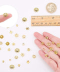 Golden Filigree Flower Bead Caps Set With 240 Pcs 12 Unique Brass Petal Ends for DIY jewelry making shown with a ruler and hand