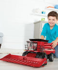 Child playing with Case IH 8240 Big Farm One Six Scale Combine With Grain Head And Corn Head Set Lights And Sounds Movable Auger