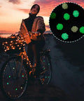Woman riding bike with glowing Plastic Bike Spoke Beads Set With 7 Styles In Assorted Colors, about 280 Pcs, on wheels.