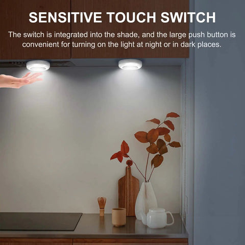 Hand touching Six Pack Portable LED Puck Tap Lights Battery Operated Night Lights under cabinet in kitchen