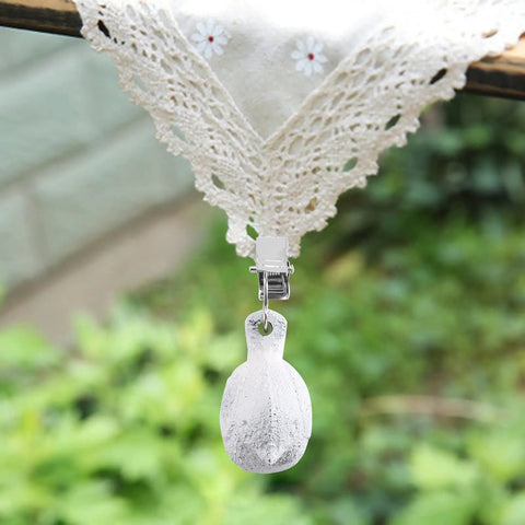 Close-up of 8 Pack Vintage Tablecloth Weights With Clip Hangers, Heavy Cast Iron Bird Weights For Outdoor Tables in garden setting.