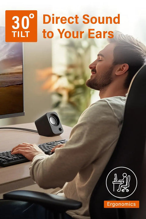 Man enjoying music at desk with 14W USB powered stereo PC speakers with compact size and 30 degree tilt design in black.