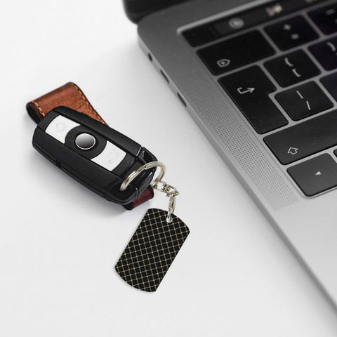 Top Shelf Gold Plated Aluminum Keychain Featuring Fresh Ribbon Grid Design Compact Rectangle Shape Rustproof Everyday Carry Daily Essential For Women And Men attached to key fob and resting by a laptop.