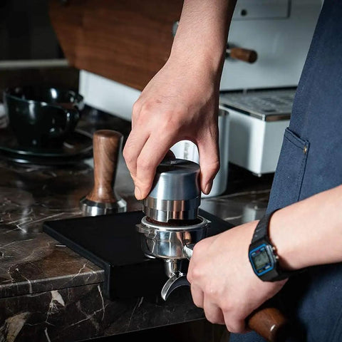 Barista using Espresso Tamping Mat For Baristas Grippy Black Food Grade Silicone Pad 8 Inch By 6 Inch Waterproof And Heat Resistant Portafilter Mat