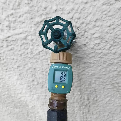 Brass Water Flow Meter For Outdoor Hoses And Lawn Sprinklers with LCD displaying gallons used, spigot connected to a wall.