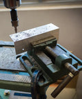 Tough As Nails Six Inch Milling Vise Heavy Duty Cast Iron Bench Clamp Precision Guiding Bar One Eighty Degree Turn Handle For Drill Press securing aluminum block during drilling.