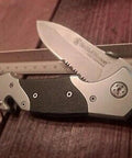 Knockout 8 Inch Folding Knife Packing A 3.3 Inch Drop Point Serrated High Carbon Stainless Blade And G10 Grip Handle on wood surface.