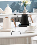 Pair Of Portable Coffee Dripper Holder And Filter Stand For Home Barista Rigs Or Weekend Warrior Campout Vibes Smooth Pour Station, black metal stand on table with kettles and cup.