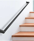 Heavy Duty Aluminum Stair Handrail For Indoor Outdoor Steps Wall Mounted Pipe Railing With Badass Black Powder Coating And Hella Strong Grip Four Feet Long And Zero Hassle Setup mounted on a wall beside wooden stairs.