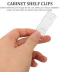 Hand holding a clear clip from 25 Piece Plastic Rectangular Shelf Pegs And Cabinet Clips Set for easy home makeover and neat storage.