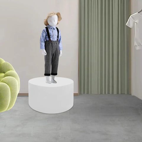 Heavy Duty 220 LB Capacity 20 Inch Round Mannequin Display Pedestal Stand In White For Retail Store Visual Merchandising And Shop Window Presentation Of Apparel Or Accessories With Iron Base showcasing a child mannequin dressed in a blue shirt on a white pedestal.