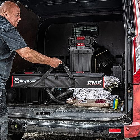 Man loading a Butt Hinge Template Kit With Fully Adjustable Router Jig into a van with storage boxes
