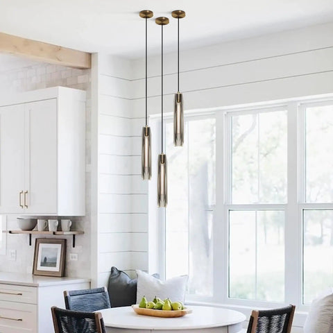 Smokey Crystal Pendant Light in Antique Brass Gold Finish over dining table, mid-century modern style with brass canopy and crystal beams.