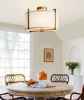 Dope Brushed Brass Four Light Flush Mount Ceiling Light With Drum Fabric Diffuser over dining table, bright natural light