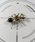 Mechanical Ant 3D Metal Model Kit with 130 Plus Pieces, Steampunk DIY Build for Adults and Teens, Creative Desk Display, Dope Gift for Engineers, Hobbyists, and Collectors. Brass and black metal ant model on a white scale mat.