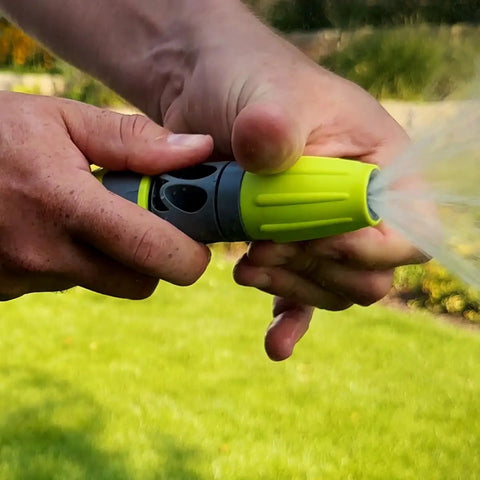Close-up of hands using a green twist nozzle with Garden Hose Kit With Quick Connect Attachments Lightweight Flexible Half Inch By Fifty Foot Hybrid Polymer Hose That Coils Easily Includes Twist Nozzle Flow Stop Coupler Spigot Adapter Hose Adapters And Hose Hanger Will Not Kink Under Pressure.